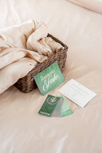 The Harmony of Jade cards and hang tags on top of TENCEL™ material bed sheet.